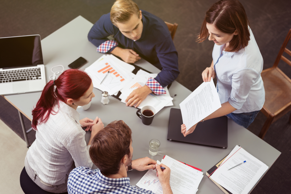 Vista aérea de un grupo de jóvenes empresarios hablando sobre el proyecto en la mesa de trabajo.-1
